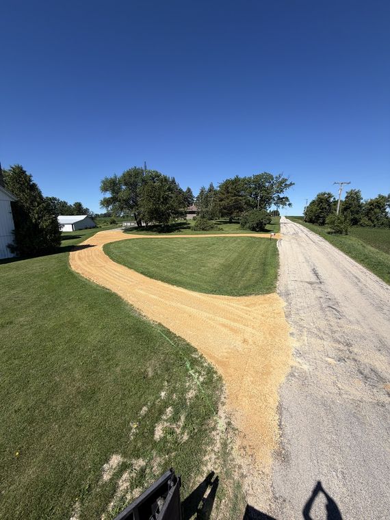 Freshly laid gravel driveway curving alongside a mowed lawn