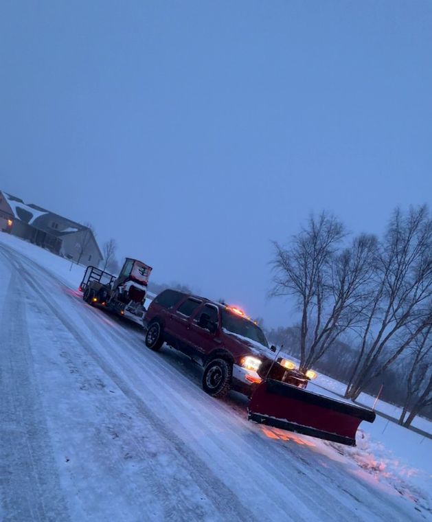 Pickup truck with a snow plow blade clearing a road during a March snowfall in Loves Park