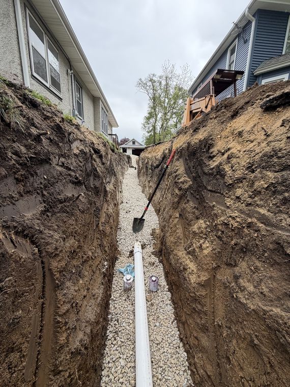 New sewer pipe laid and bedded in stone at the bottom of a deep trench