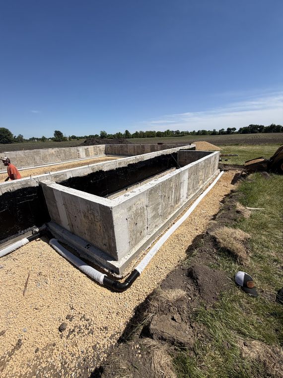 Poured foundation walls with drain tile and stone backfill in place