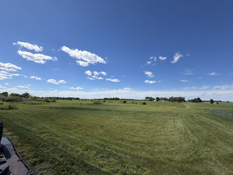 Wide mowed hay field under an open summer sky
