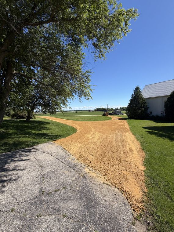 New gravel driveway curving from the road up to a farmstead