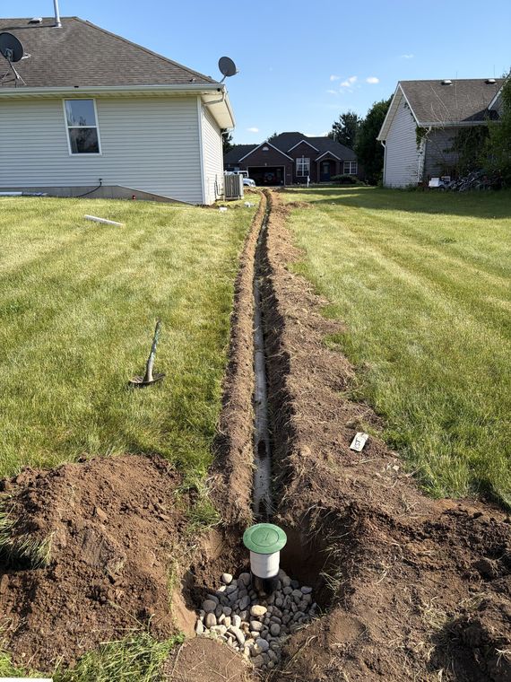 Long drain tile trench across a back lawn with a catch basin set in place
