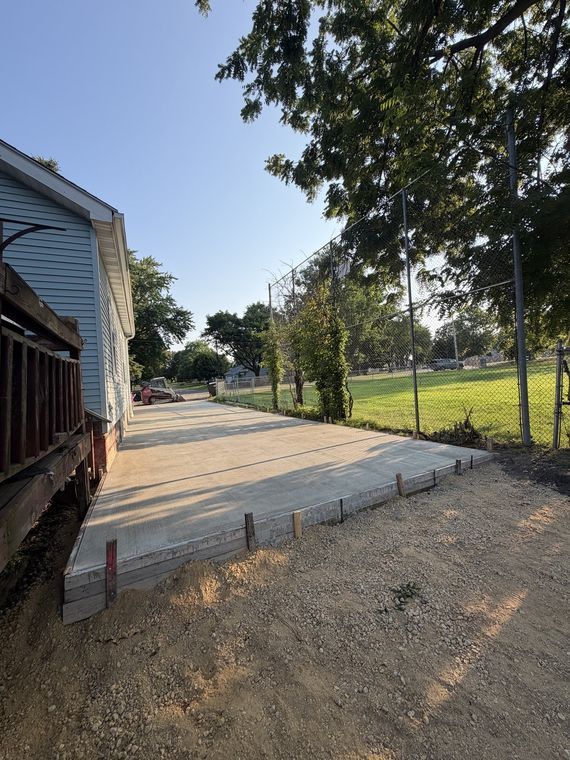 Newly poured concrete driveway running alongside a house