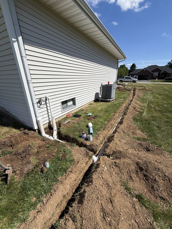 Drain line trench running along the foundation of a house