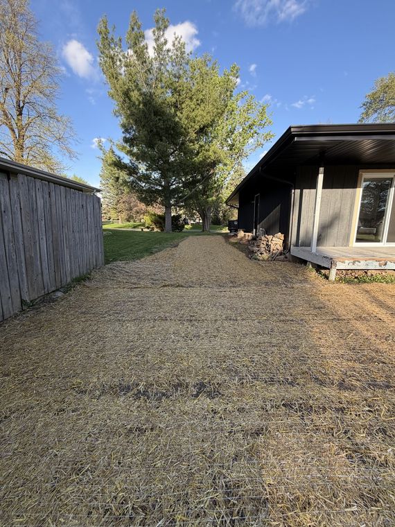 Compacted gravel driveway running alongside a house and outbuilding