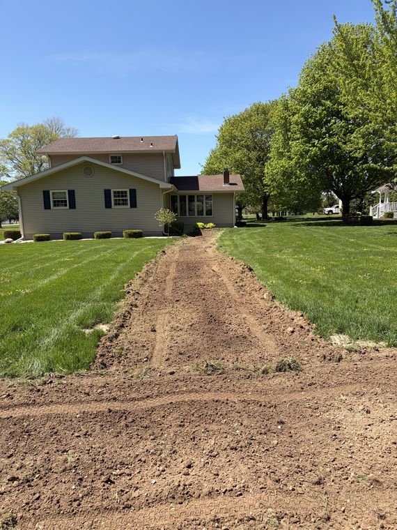 Restored lawn with a fresh soil scar where a utility line was run