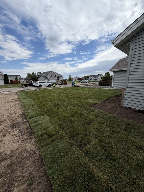 Graded and sodded yard beside a new home with the street beyond